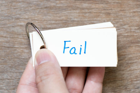 Hand hold flash card with handwriting in word fail on wood backgroundの写真素材