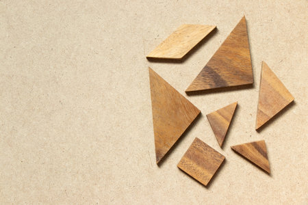 Straggled tangram puzzle  wait to complete the shape on wood background with copy spaceの写真素材