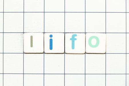 Colorful tile letter in word LIFO (abbreviation of last in first out) on white grid backgroundの写真素材