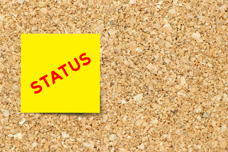 Yellow note paper with word status on cork board background with copy spaceの写真素材