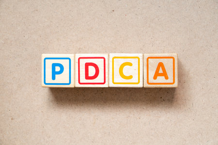 Alphabet letter block in word PDCA (Abbreviation of plan do check act) on wood backgroundの写真素材