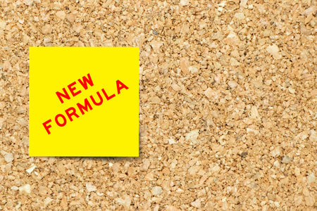 Yellow note paper with word new formula on cork board background with copy spaceの写真素材