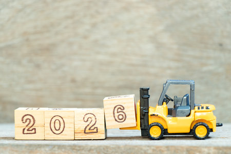 Toy forklift hold letter block 6 to complete word 2026 on wood background