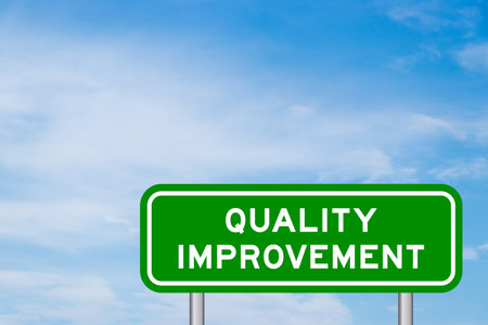 Green color transportation sign with word quality improvement on blue sky with white cloud backgroundの写真素材
