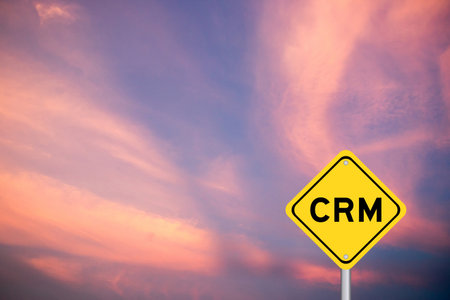 Yellow transportation sign with word CRM (Abbreviation of Customer Relationship Management) on violet color sky backgroundの写真素材