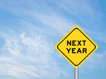 Yellow transportation sign with word next year on blue color sky backgroundの写真素材