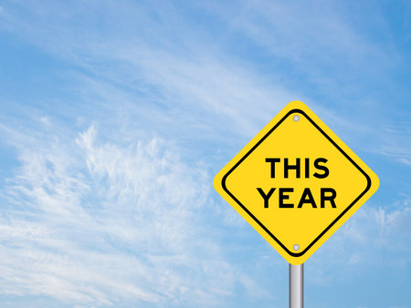Yellow transportation sign with word this year on blue color sky backgroundの写真素材