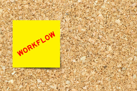 Yellow note paper with word workflow on cork board background with copy spaceの写真素材