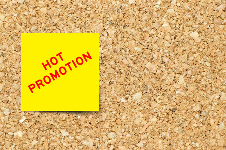 Yellow note paper with word hot promotion on cork board background with copy space