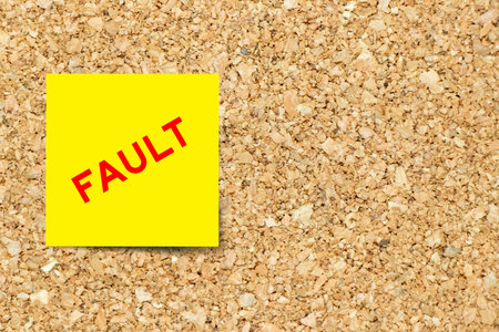 Yellow note paper with word fault on cork board background with copy space