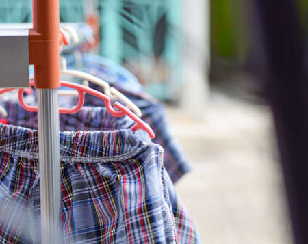 Dry clothes and school uniform hanging on rack with blurry fence forgroundの写真素材