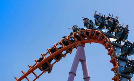 Group of people playing roller coaster red rail with blue sky at amusement park,so very excited.の写真素材