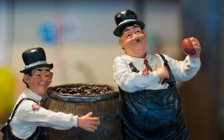 Two of funny clay doll hold barrel of fresh coffee beans