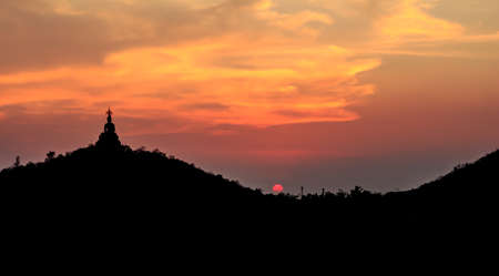 Sunset behind the Buddha on mountain , Ratchaburi Thailand. Process color.の写真素材