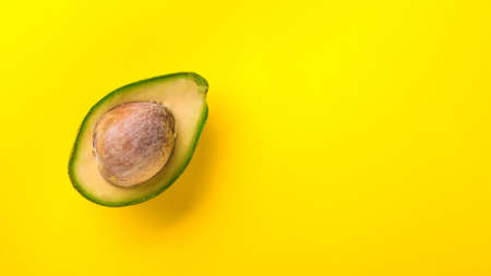 Half of avocado on yellow background