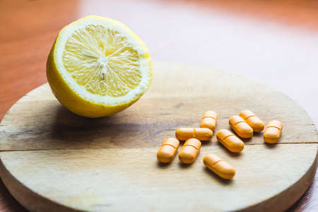Slice of lemon and vitamin C pills in the wooden spoon on the tableの写真素材