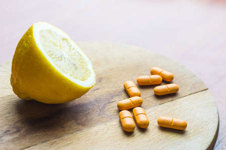 Slice of lemon and vitamin C pills in the wooden spoon on the tableの写真素材
