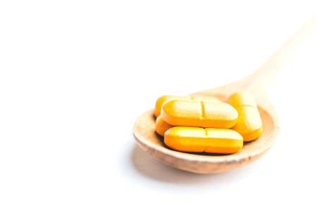 Vitamin C pills in wooden spoon isolated on white backgroundの写真素材