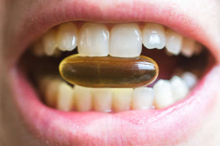 Pill with omega fatty acids between the teethの写真素材