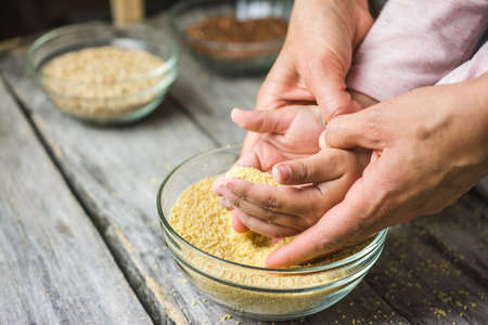 Mother and child's hands grabbing millet seeds from the glass bowl
