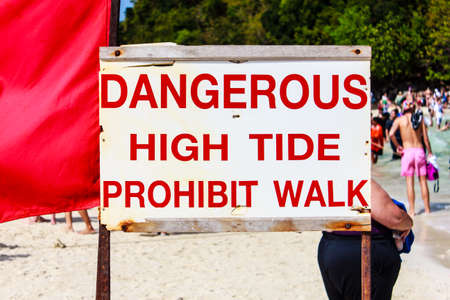Beach sign that says, Dangerous High Tide Prohibit Walk.