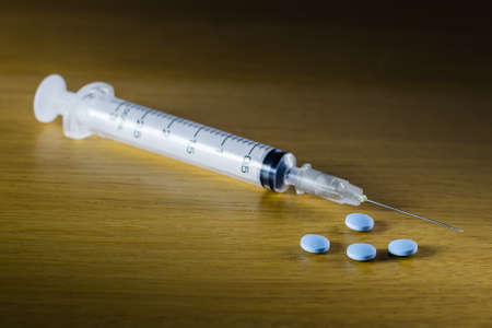 Drug syringe and cooked heroin on wood tableの写真素材