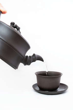 pouring tea from teapot to a cup on a white backgroundの写真素材