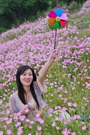 a girl in field with pinwheel in hand and flowers aroundの写真素材