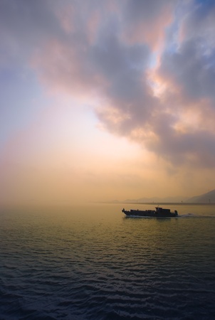 a boat sailing in the sea at sunset の写真素材