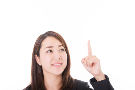 Portrait of young business woman pointing up at white backgroundの写真素材