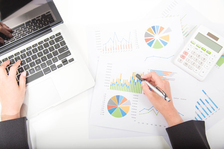 Businesswoman hands using laptop computer and writing on business graph information diagramの写真素材