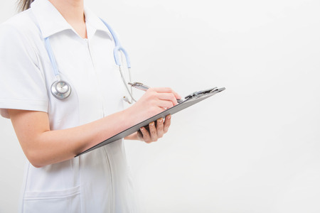 Hands of young nurse writing on a clipboardの写真素材