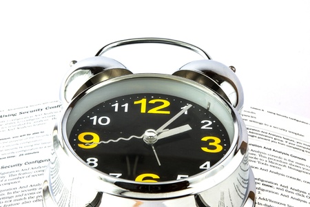 Silver alarm clock resting on a bookの写真素材