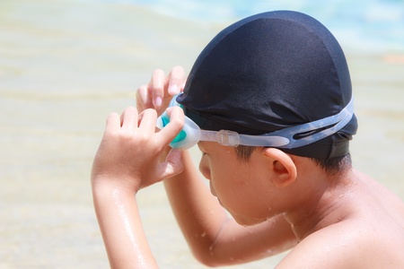 An asian boy touch a goggle to wear before swimの写真素材