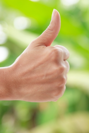 Hand with thumb up  against nature backgrioundの写真素材