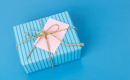 Beautiful blue gift box with tag on colorful backgroundの写真素材