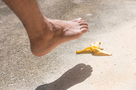 Foot before slipping banana peel on cement floorの写真素材