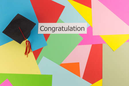 Graduation cap and word congratulation on colorful paper backgroundの写真素材