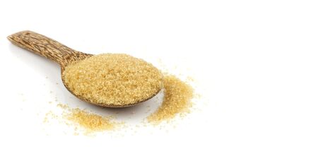 Heap of  brown cane sugar on wooden spoon against  white backgroundの写真素材