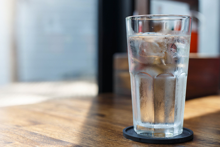 Glass of cold drinking water on table against blur background