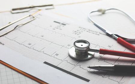 Healthcare and medical concept - Red stethoscope,pen and clipboard on hearybeat result paperの写真素材