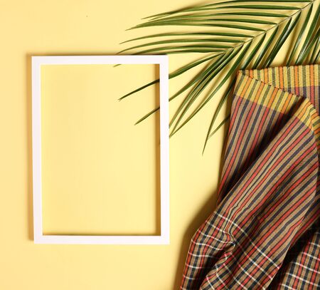 Summer background made from thai fabric and palm leaves on pastel yellow background, flay lay, copy spaceの写真素材