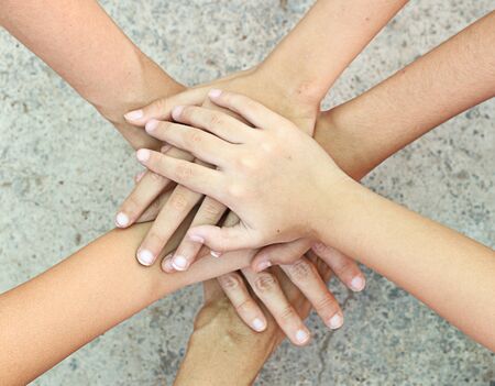 Teamwork concept - People holding hand together against concrete  background