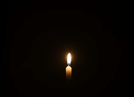 Light of hope - Candle is burning against black backgroundの写真素材