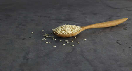 A spoon of white sesame in the middle of black background