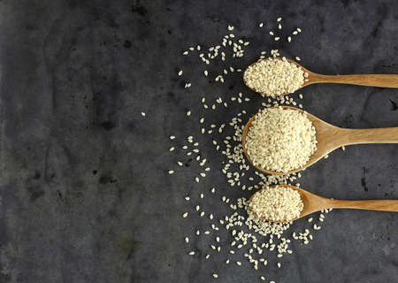 Top view of dry sesame seed  on wooden spoon against black backgroundの写真素材