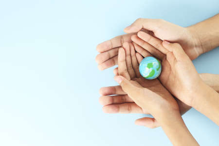 Happy earth day - Top view of two hands hold earth on blue background - Global warming - save the earth - world environment dayの写真素材