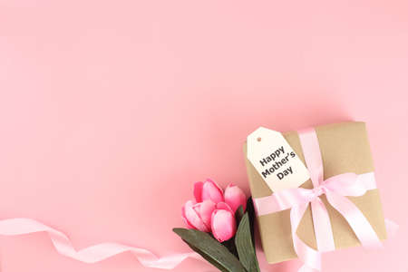 Mother's day background. Top view of gift box with pink bows - long ribbon , beautiful flowers and card on pastel pink background with copy spaceの写真素材