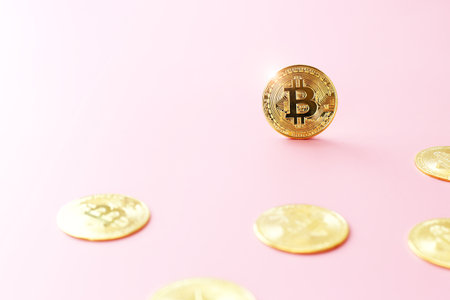 Close up golden bitcoin coin on light pink background. Cryptocurrency symbol. The shiny bitcoin gold coin stands out among other coins with copy space.の写真素材