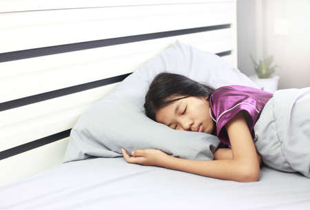 Asian girl sleeping during illness - she has a pale face sleep in bed and blanket. Bad health need rest.の写真素材